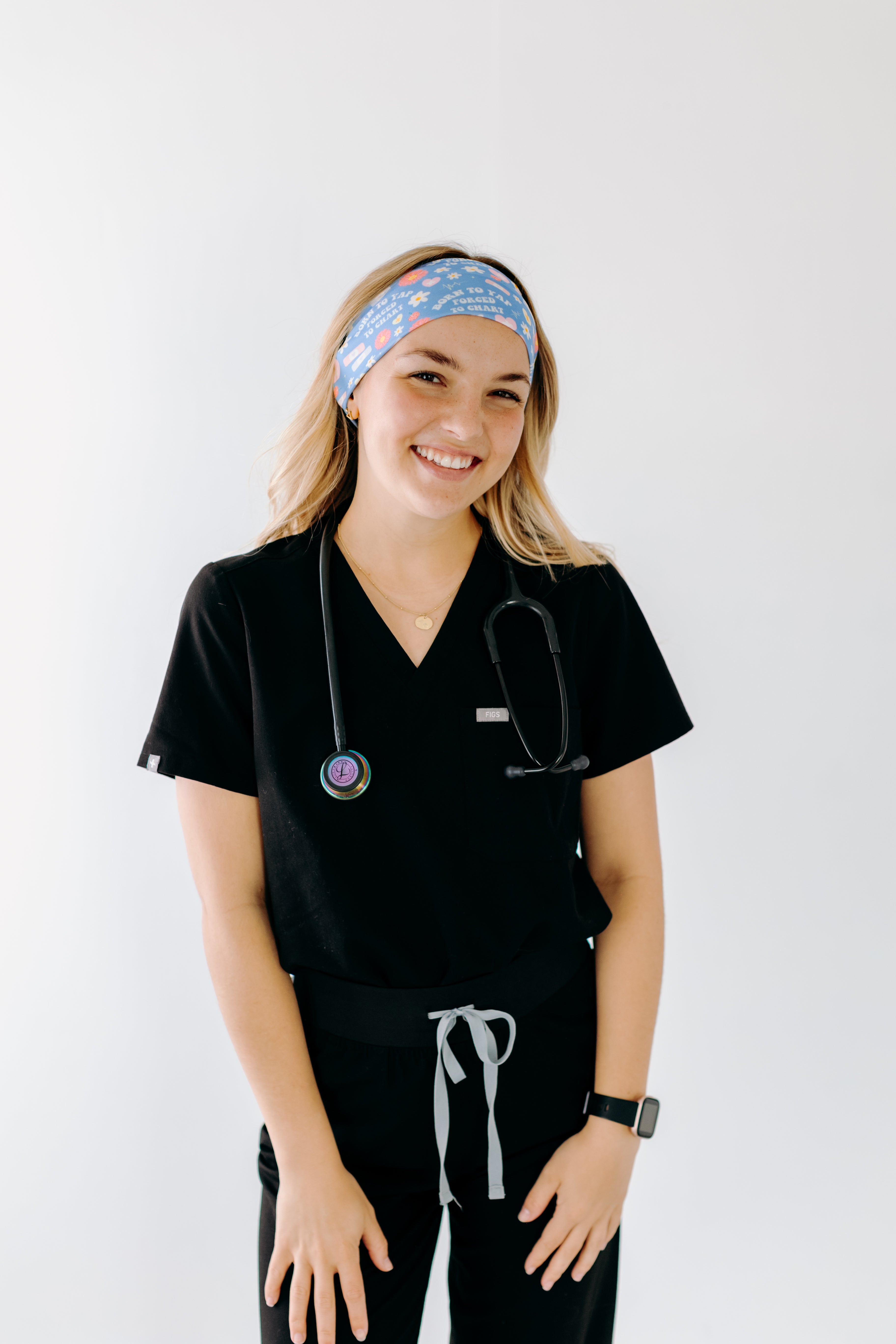 A nurse smiling with long hair while wearing the Born to Yap Forced to Chart headband for cute hairstyles and comfortable all-day wear.