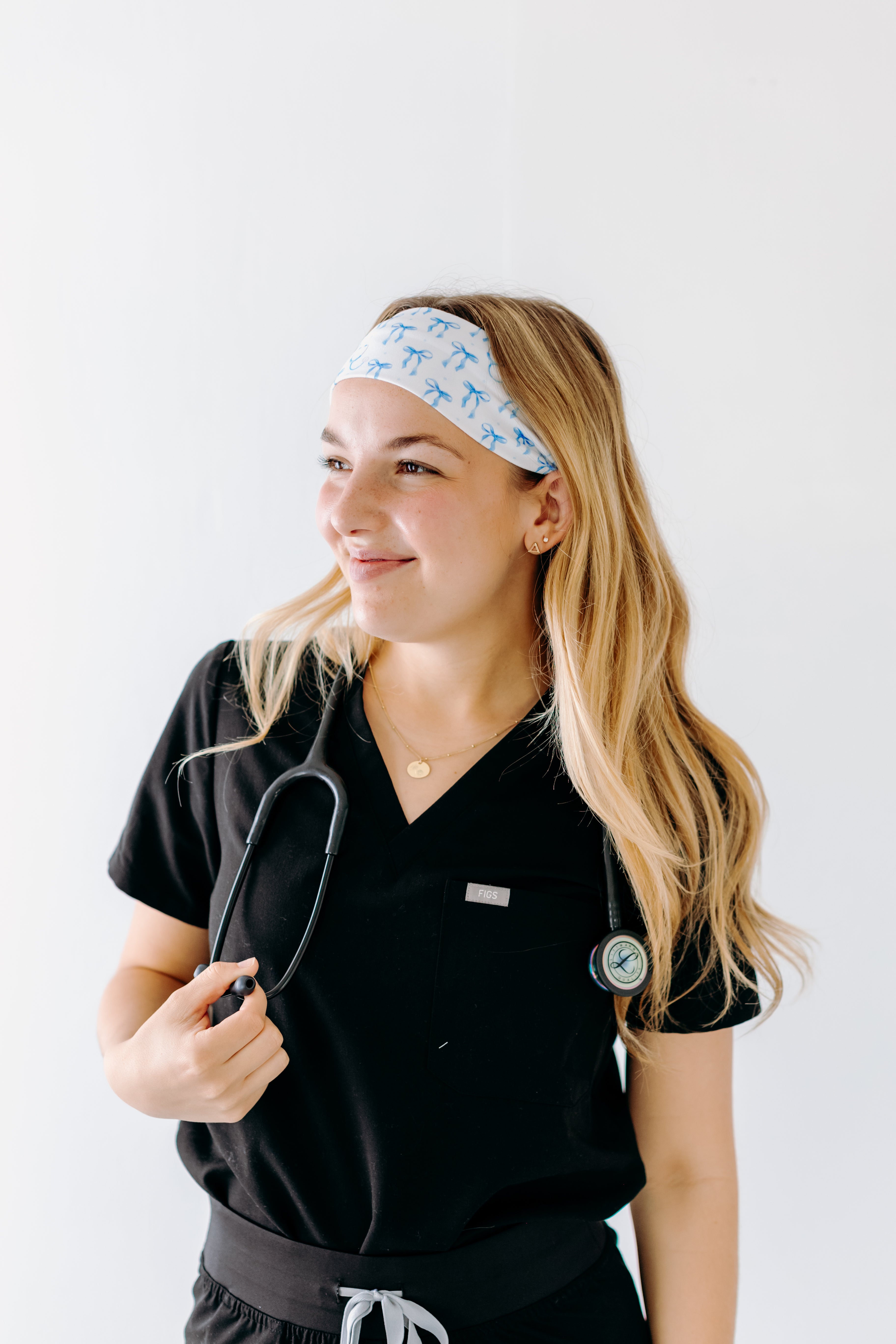 A nurse smiling with long hair while wearing the Nurses Do It Better headband for cute hairstyles and comfortable all-day wear.