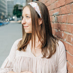 Woman smiling, wearing Preston Floral on Ivory headband from The Sarah Wallace Collection, showcasing its soft, stretchy fabric and versatile 3-in-1 twist style.
