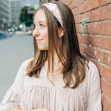 Woman smiling, wearing Preston Floral on Ivory headband from The Sarah Wallace Collection, showcasing its soft, stretchy fabric and versatile 3-in-1 twist style.