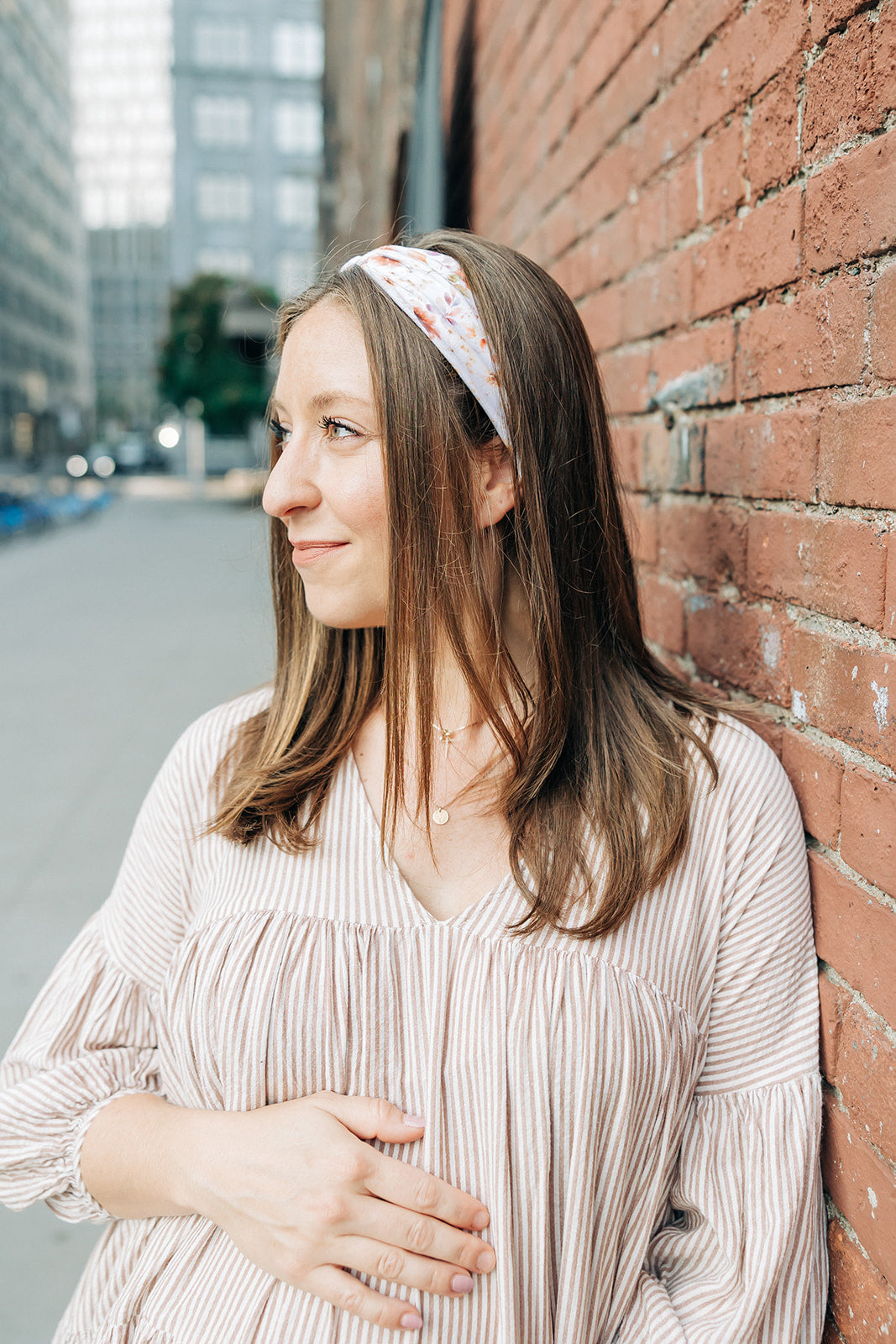 Woman smiling, wearing Preston Floral on Ivory headband from The Sarah Wallace Collection, showcasing its soft, stretchy fabric and versatile 3-in-1 twist style.