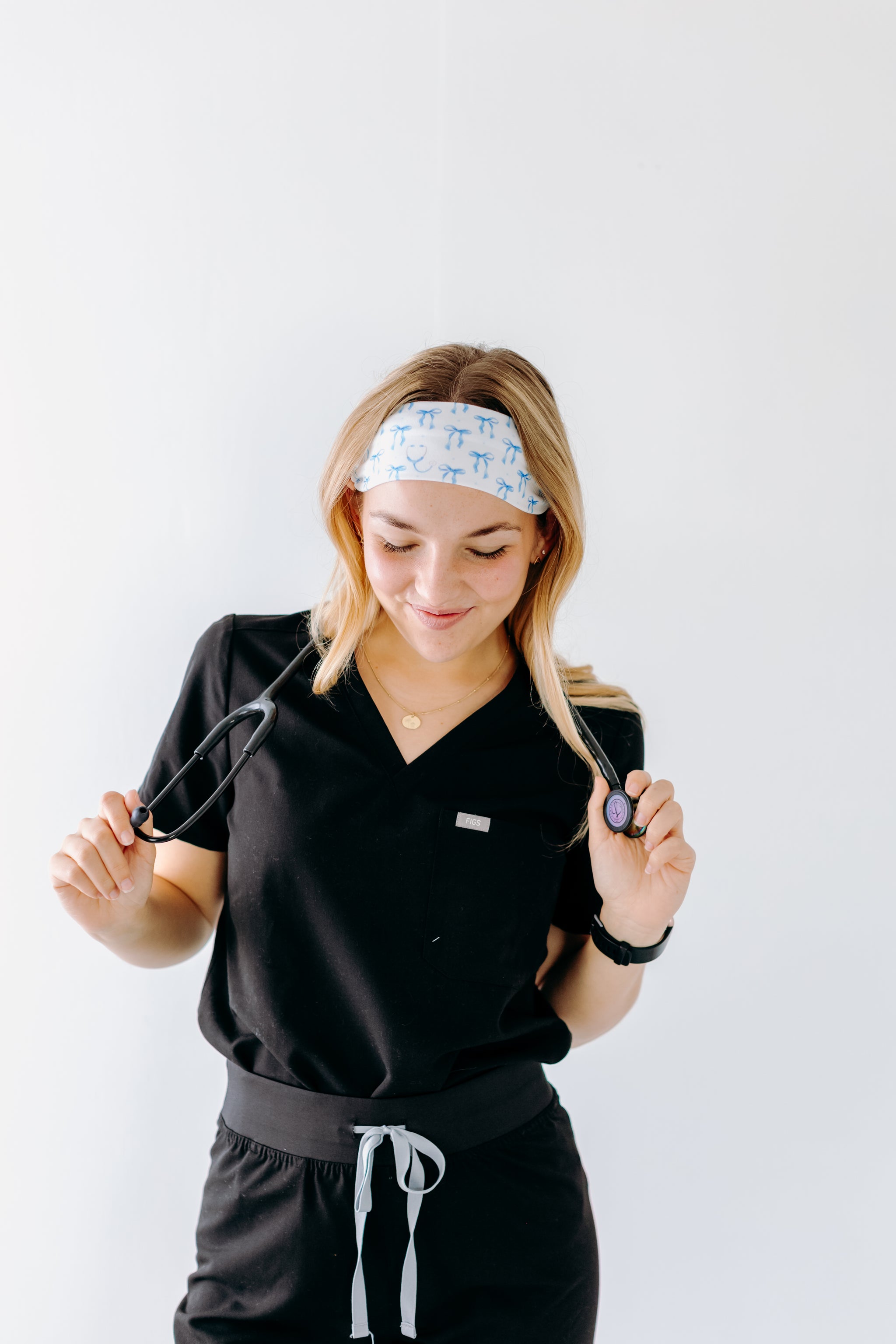 A nurse smiling with long hair while wearing the Nurses Do It Better headband for cute hairstyles and comfortable all-day wear.