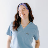 A nurse smiling with long hair while wearing the Ask Us About Our Warm Blankets headband for cute hairstyles and comfortable all-day wear.