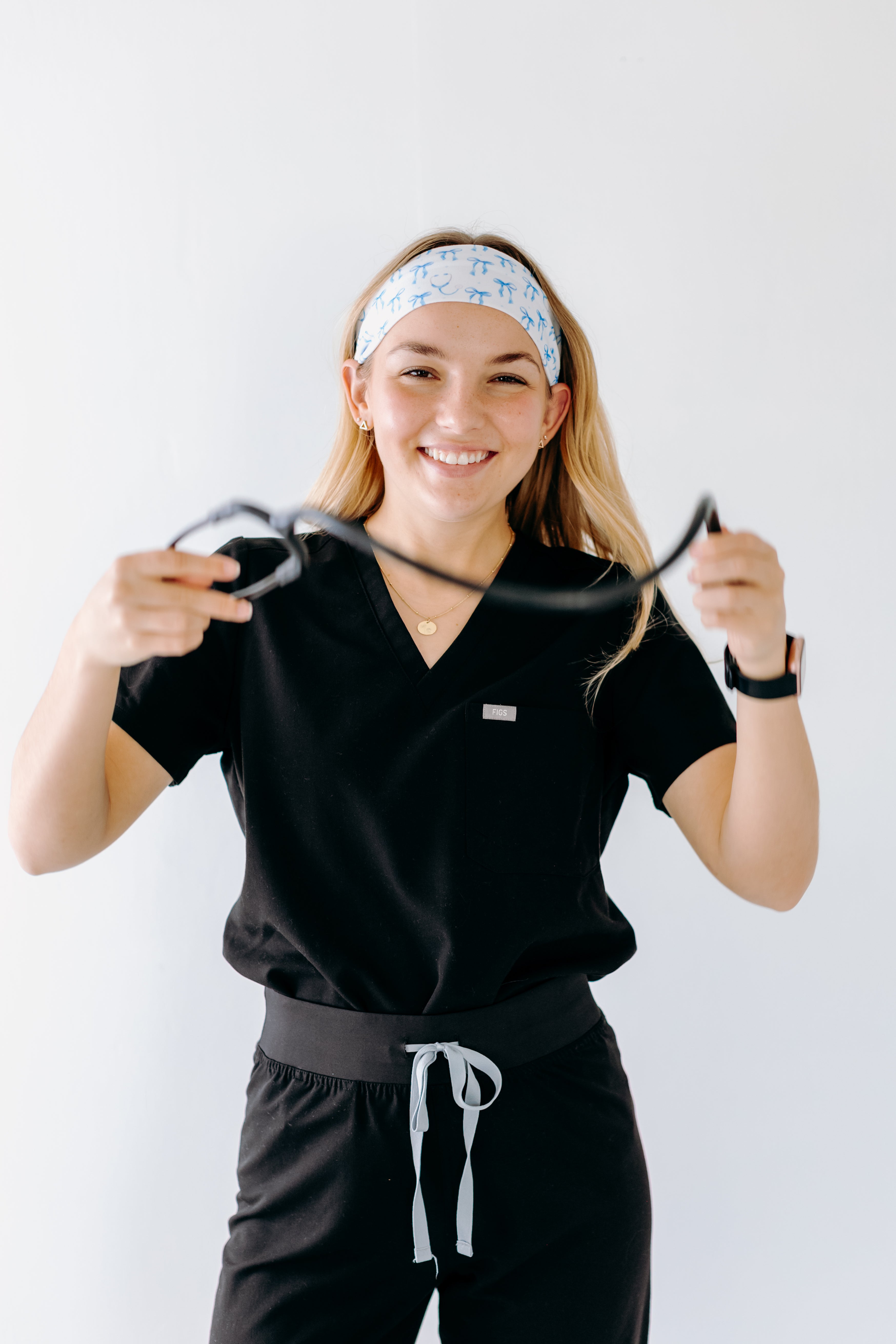 A nurse smiling with long hair while wearing the Nurses Do It Better headband for cute hairstyles and comfortable all-day wear.