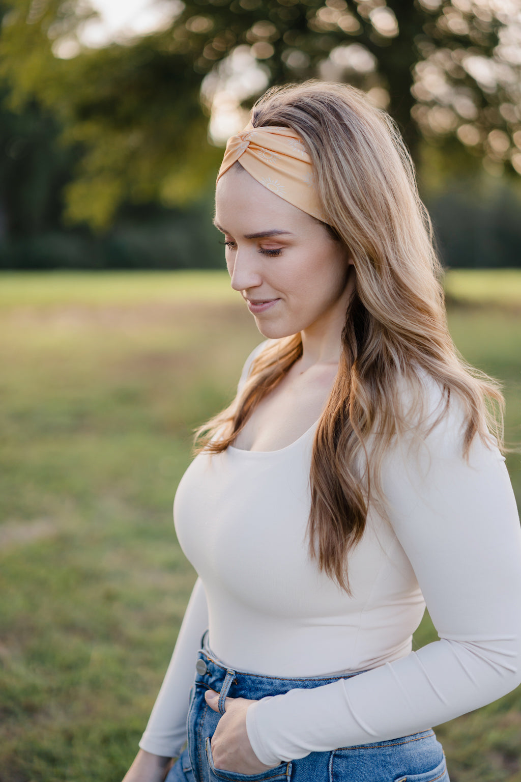 Woman smiling outdoors, wearing the Bring the Weather headband from The Jen Hamilton Collection, showcasing its versatile, non-slip, buttery-soft design.