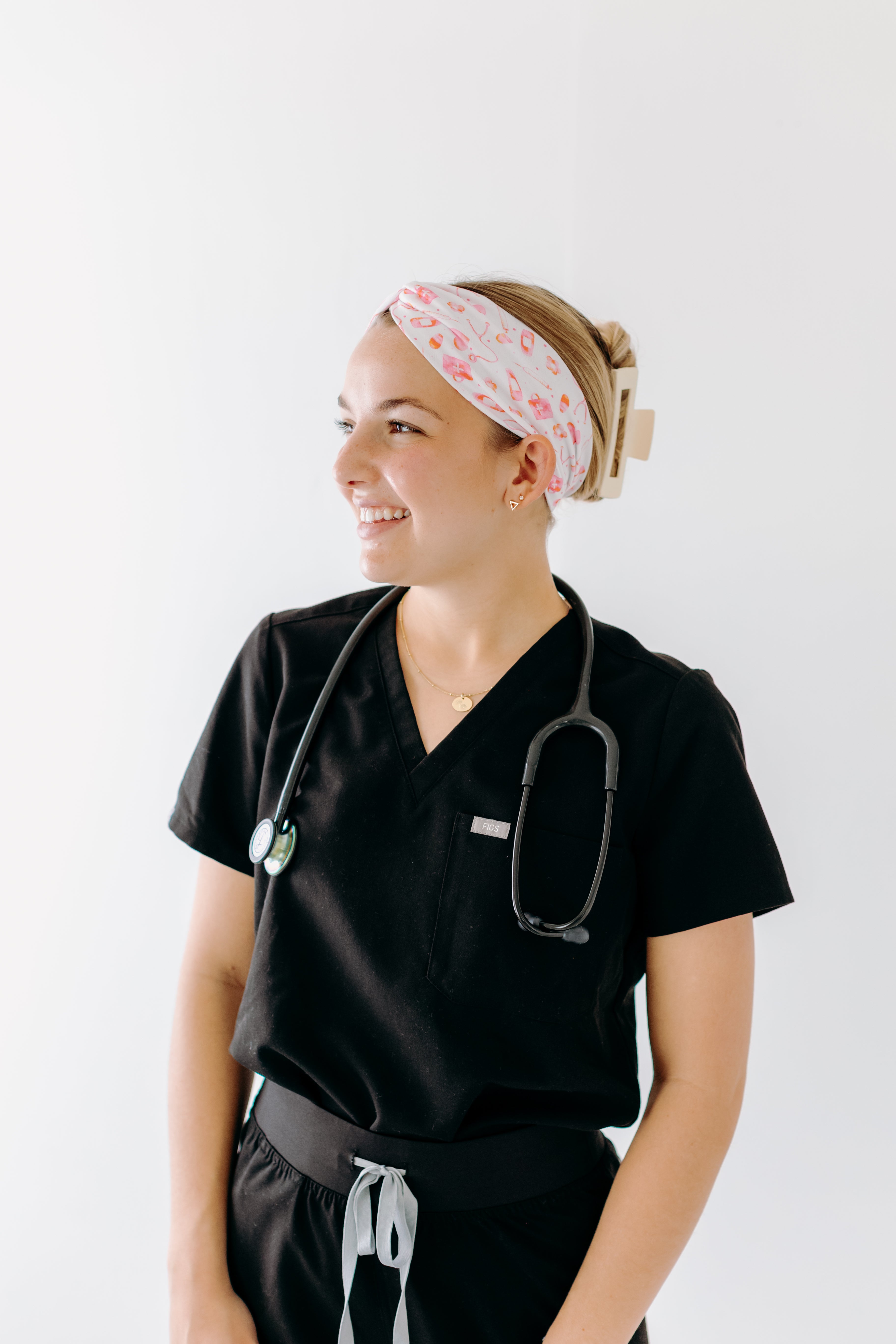 A nurse smiling with hair pinned up while wearing the I'm Just Here For The Free Gloves headband for cute hairstyles and comfortable all-day wear.
