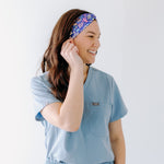 A nurse smiling with long hair while wearing the Ask Us About Our Warm Blankets headband for cute hairstyles and comfortable all-day wear.