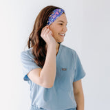 A nurse smiling with long hair while wearing the Ask Us About Our Warm Blankets headband for cute hairstyles and comfortable all-day wear.