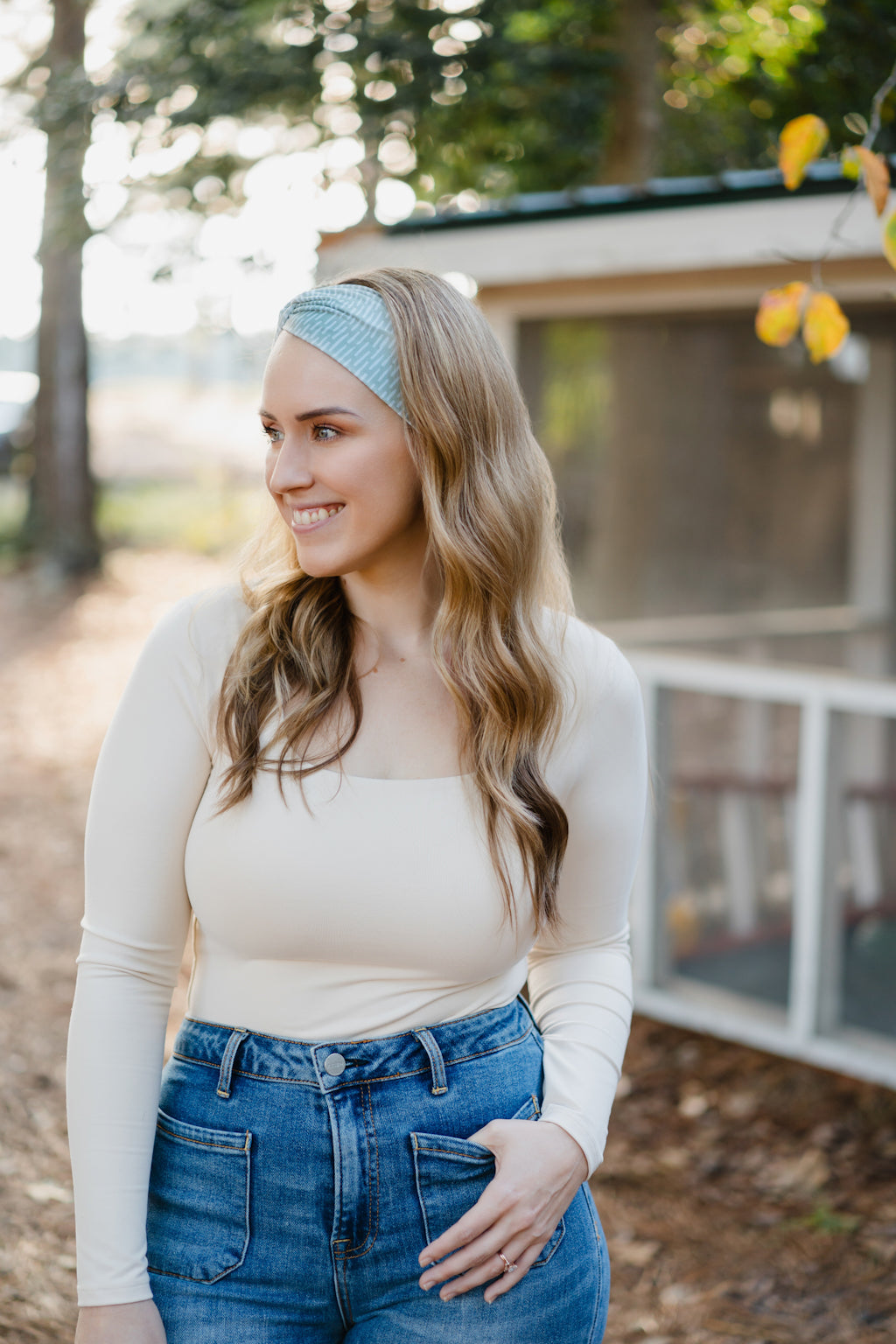 Beautifully Unconventional headband, worn by a smiling woman with long hair, showcasing its versatile 3-in-1 twist style and comfortable fit from the Jen Hamilton Collection.