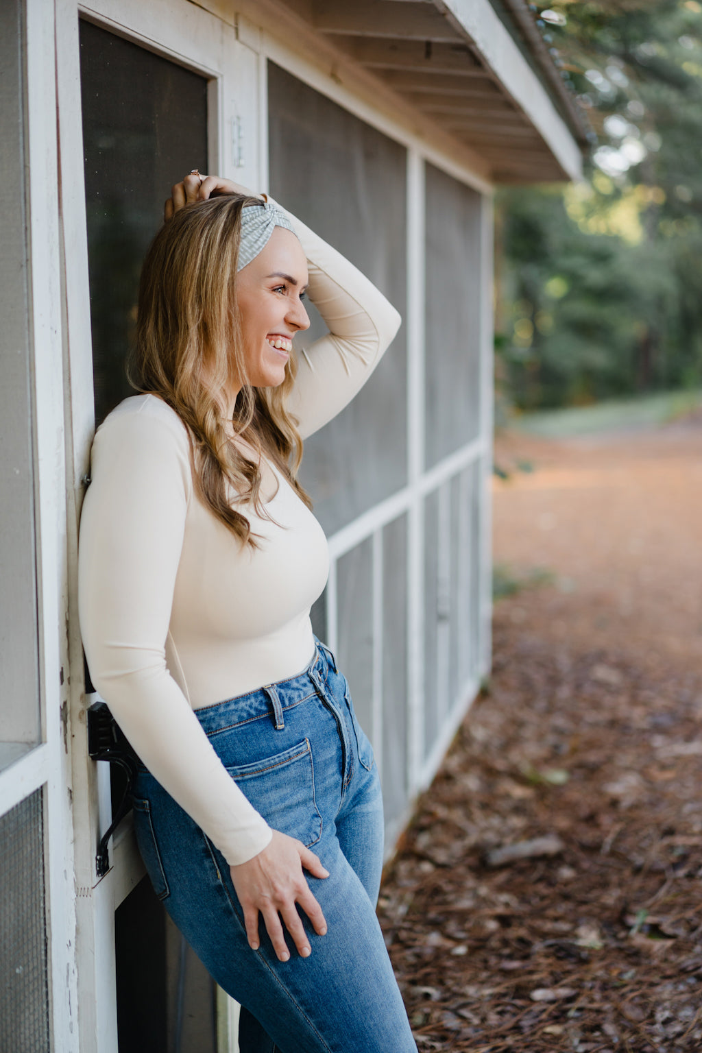 Beautifully Unconventional headband, worn by a smiling woman with long hair, showcasing its versatile 3-in-1 twist style and comfortable fit from the Jen Hamilton Collection.