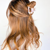 A woman wearing the Head in the Clouds Lilac Clip, a 2-inch long claw clip, adding style to her hair.