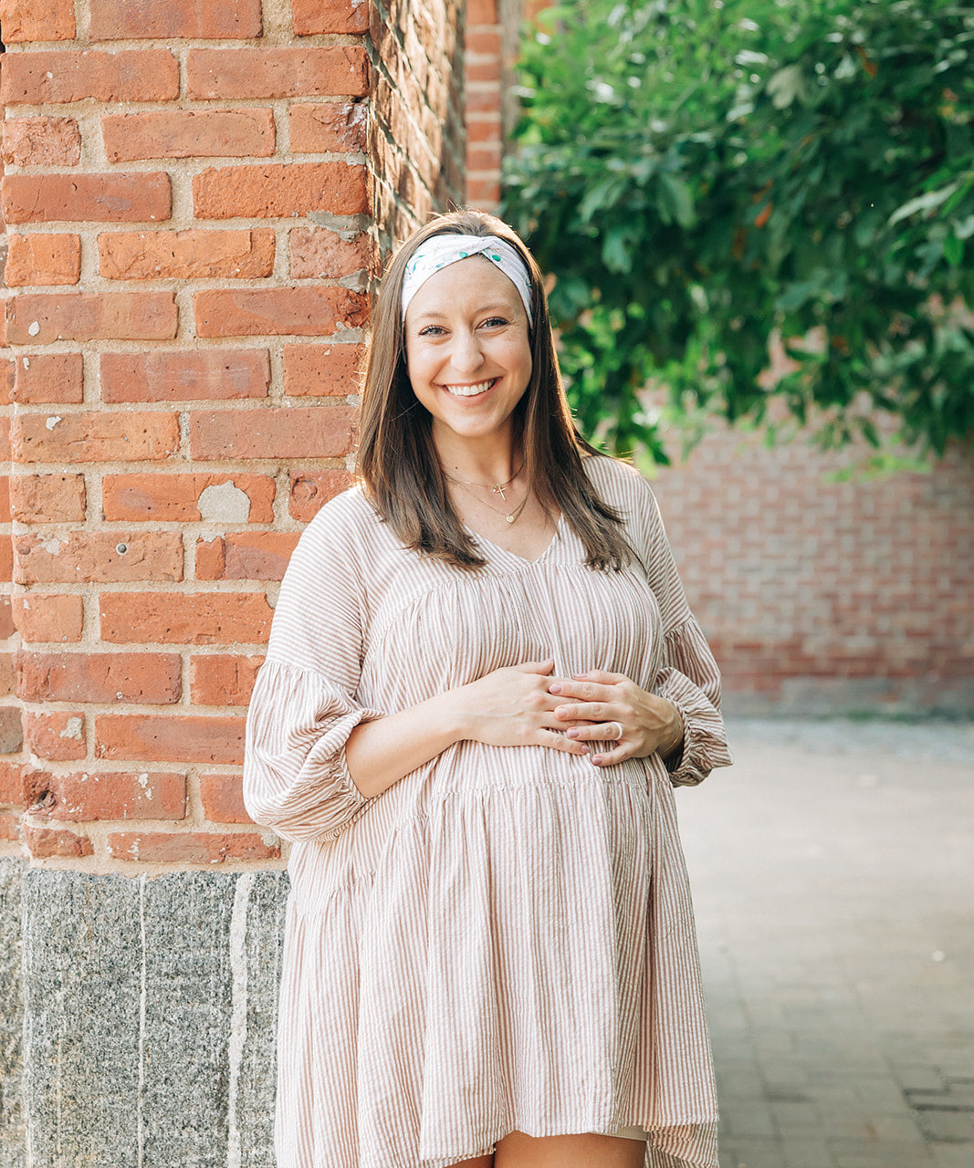 A woman smiling and confidently wearing the Springtime in Brooklyn headband from The Sarah Wallace Collection, showcasing its versatile twist style and non-slip design.