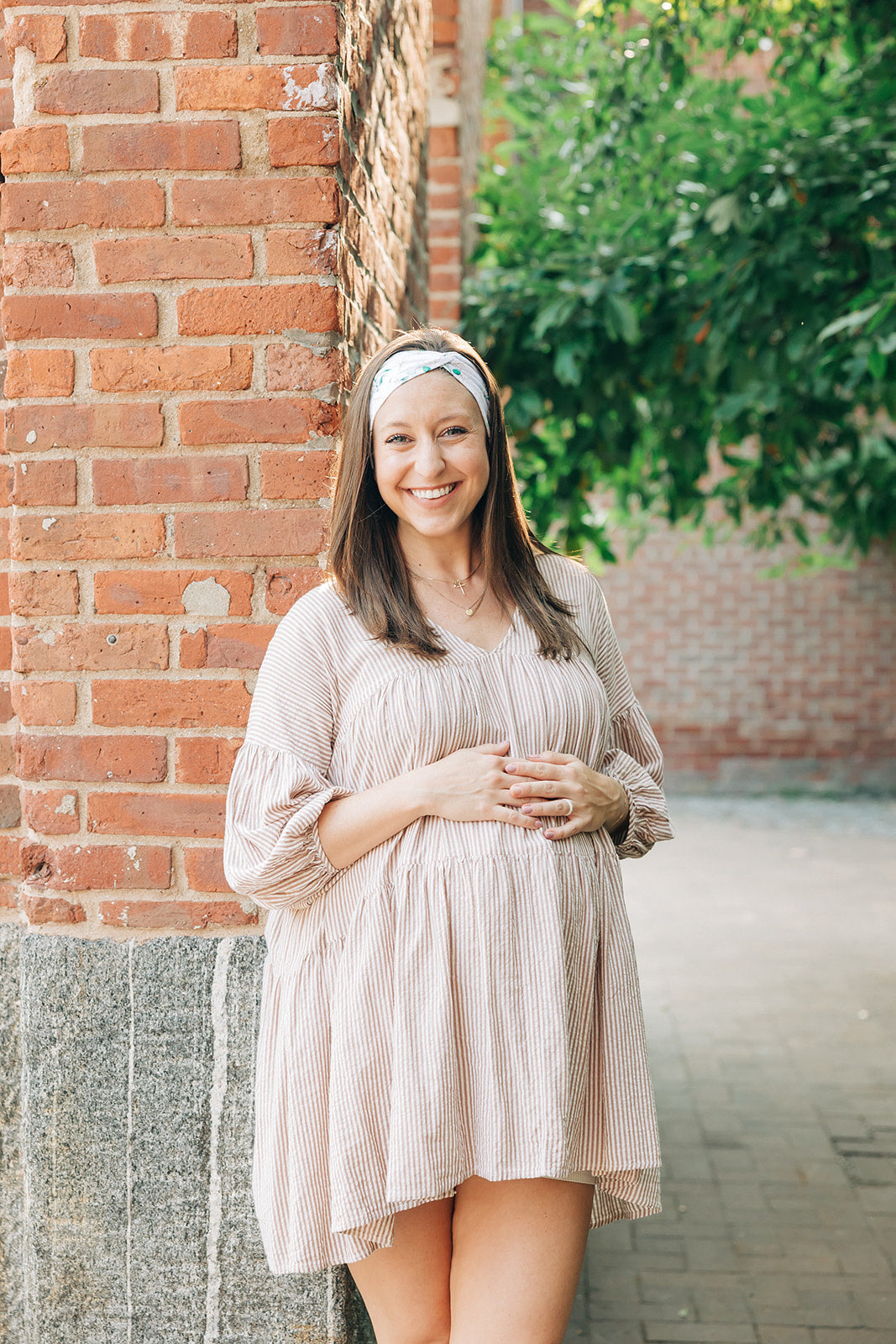 A woman smiling and confidently wearing the Springtime in Brooklyn headband from The Sarah Wallace Collection, showcasing its versatile twist style and non-slip design.