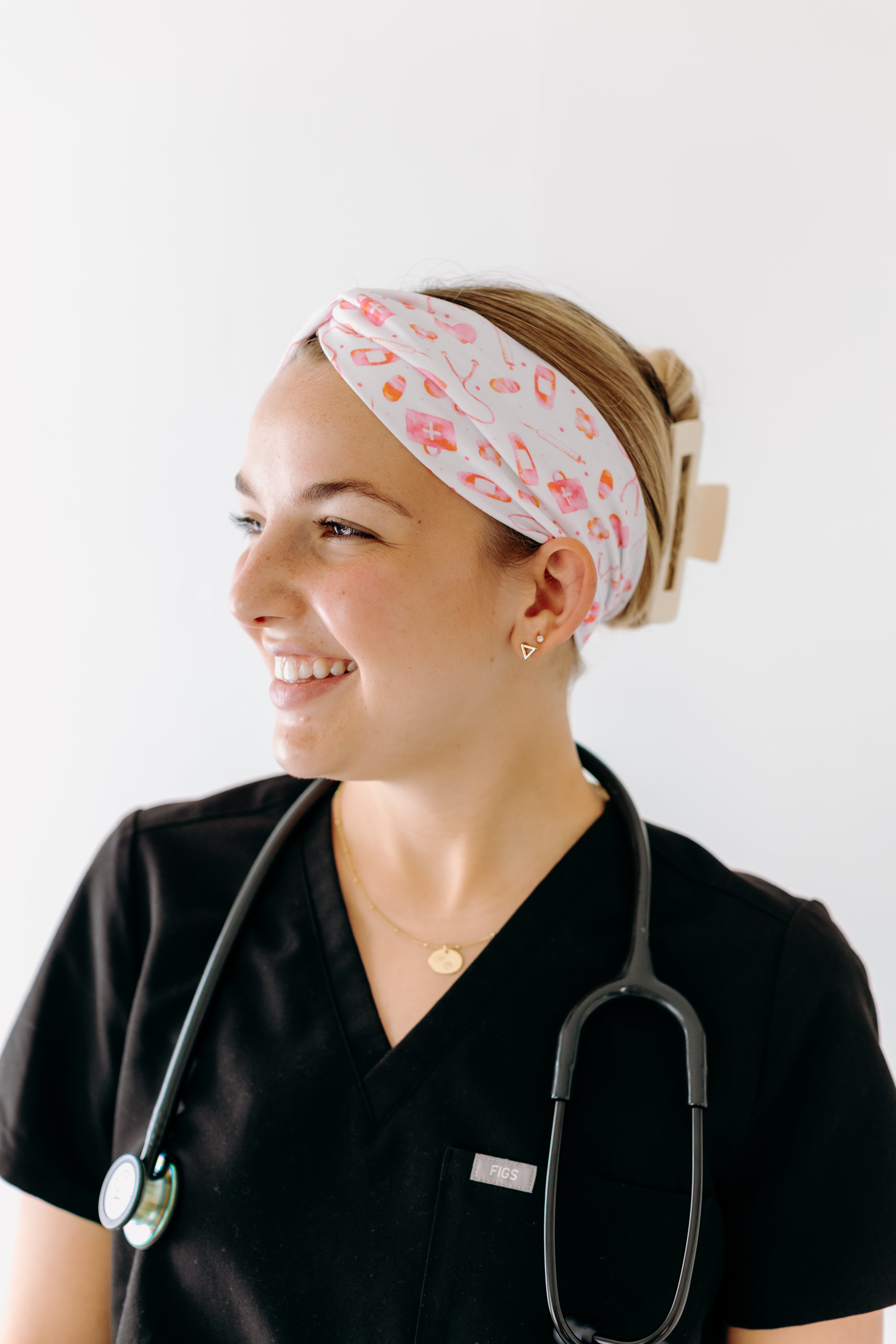 A nurse smiling with hair pinned up while wearing the I'm Just Here For The Free Gloves headband for cute hairstyles and comfortable all-day wear.