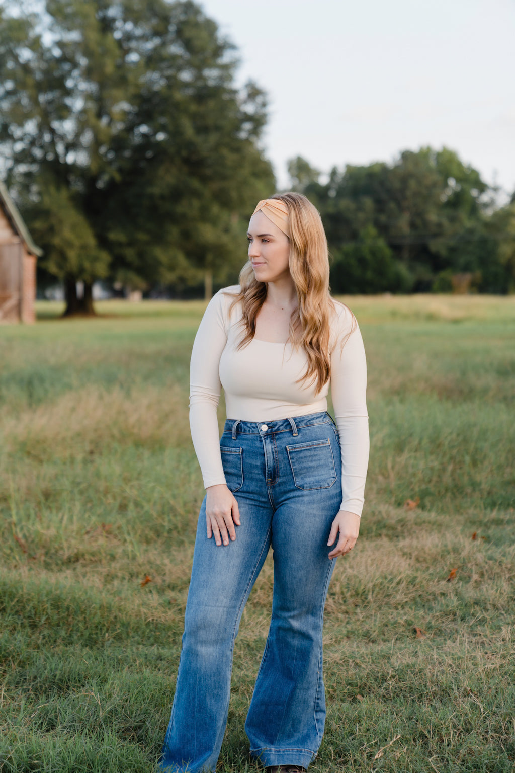 Woman smiling outdoors, wearing the Bring the Weather headband from The Jen Hamilton Collection, showcasing its versatile, non-slip, buttery-soft design.