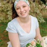 Woman smiling while wearing the Hope Floral on Ivory headband, the perfect non-slip accessory for work or workouts.