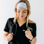 A nurse smiling with long hair while wearing the Nurses Do It Better headband for cute hairstyles and comfortable all-day wear.