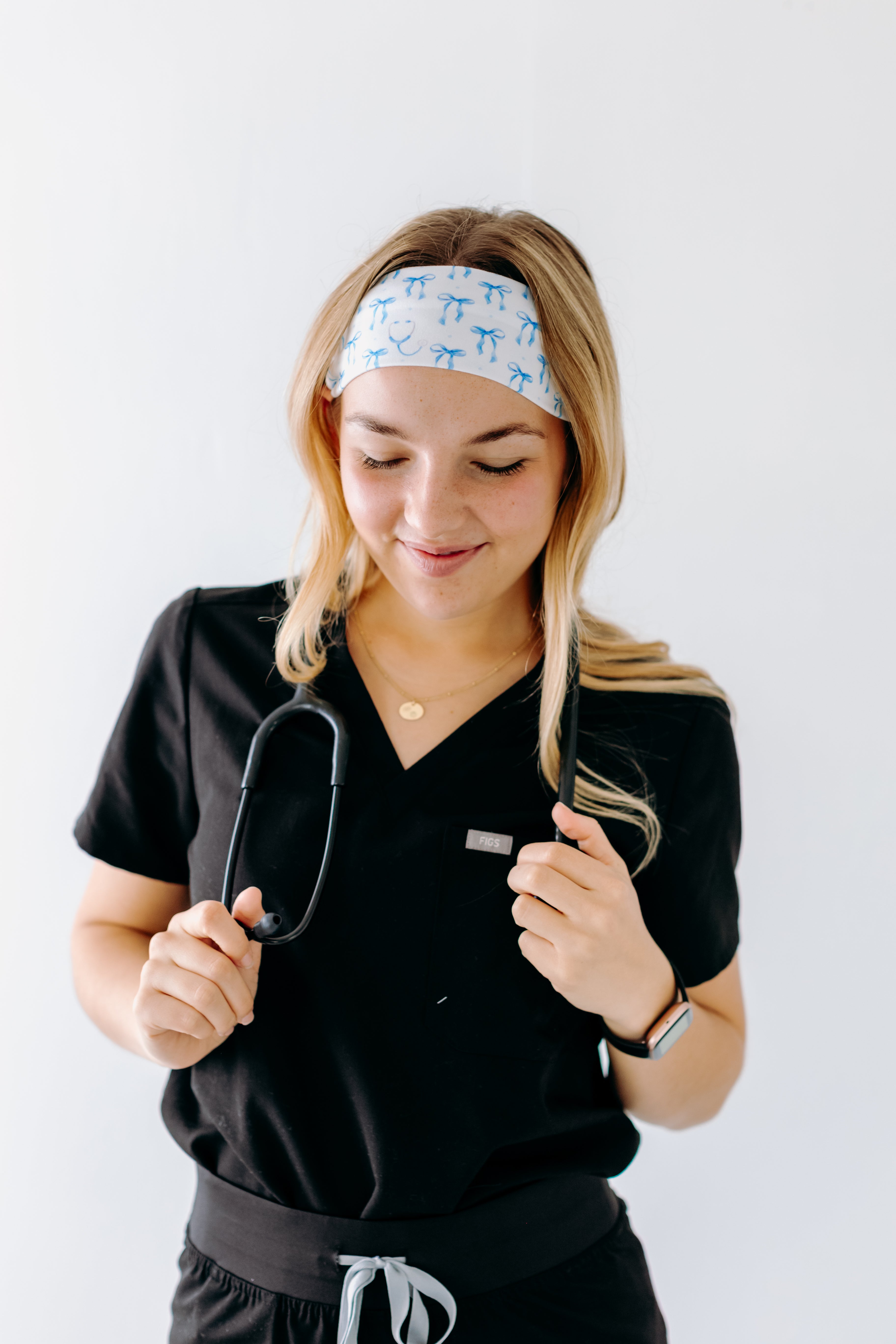 A nurse smiling with long hair while wearing the Nurses Do It Better headband for cute hairstyles and comfortable all-day wear.