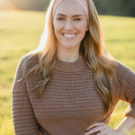 Woman smiling, wearing a Spiced Peach headband, showcasing its versatility and comfort, ideal for workouts or casual wear, made from soft, stretchy poly-knit blend.