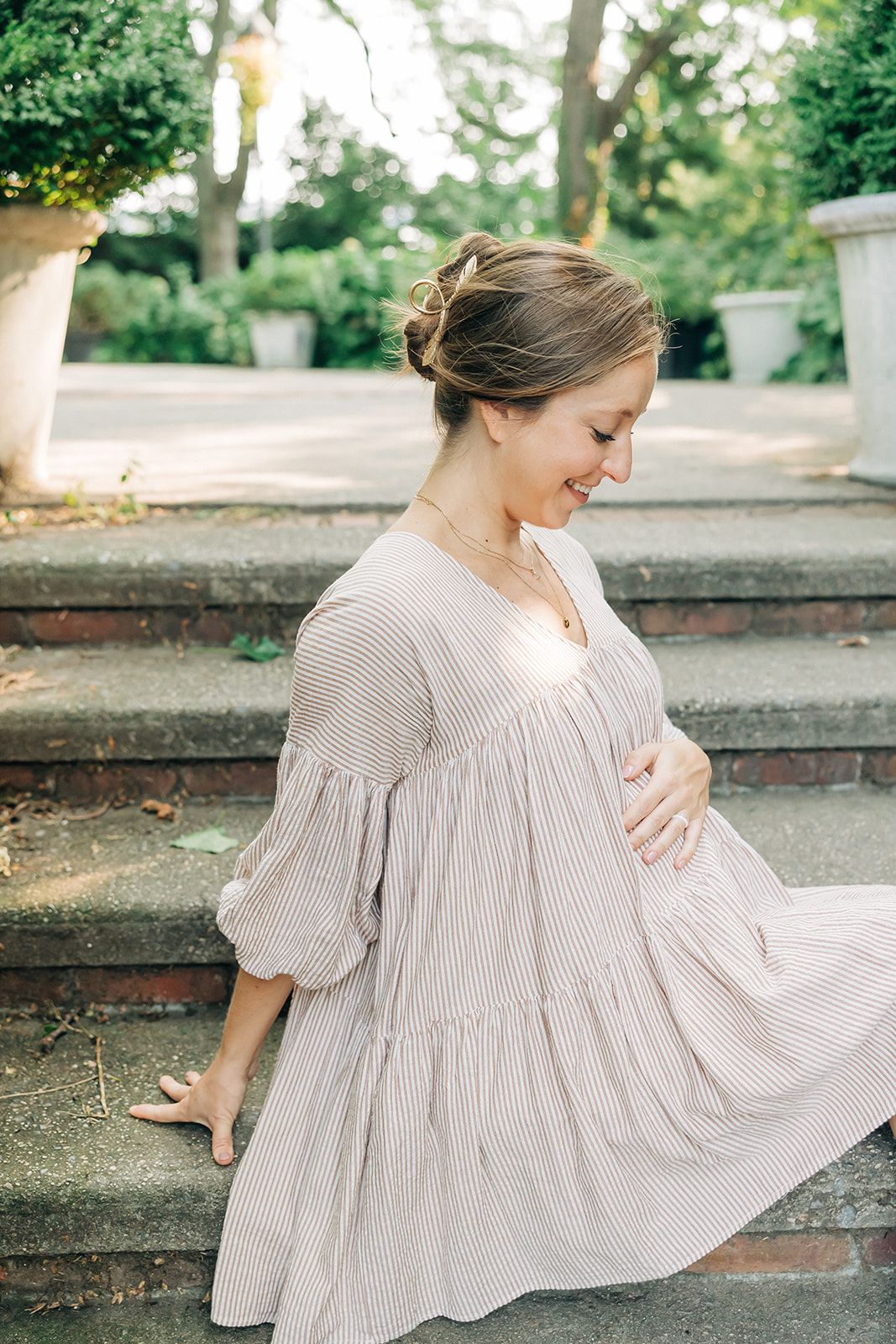 Woman wearing a gold hair clip shaped like a feather in a bun, showcasing the One of a Kind Lilac Clip from The Sarah Wallace Collection.
