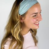 Woman wearing the Lost in Space headband, showcasing its versatile 3-in-1 twist style and buttery-soft, non-slip fabric, ideal for work or play.