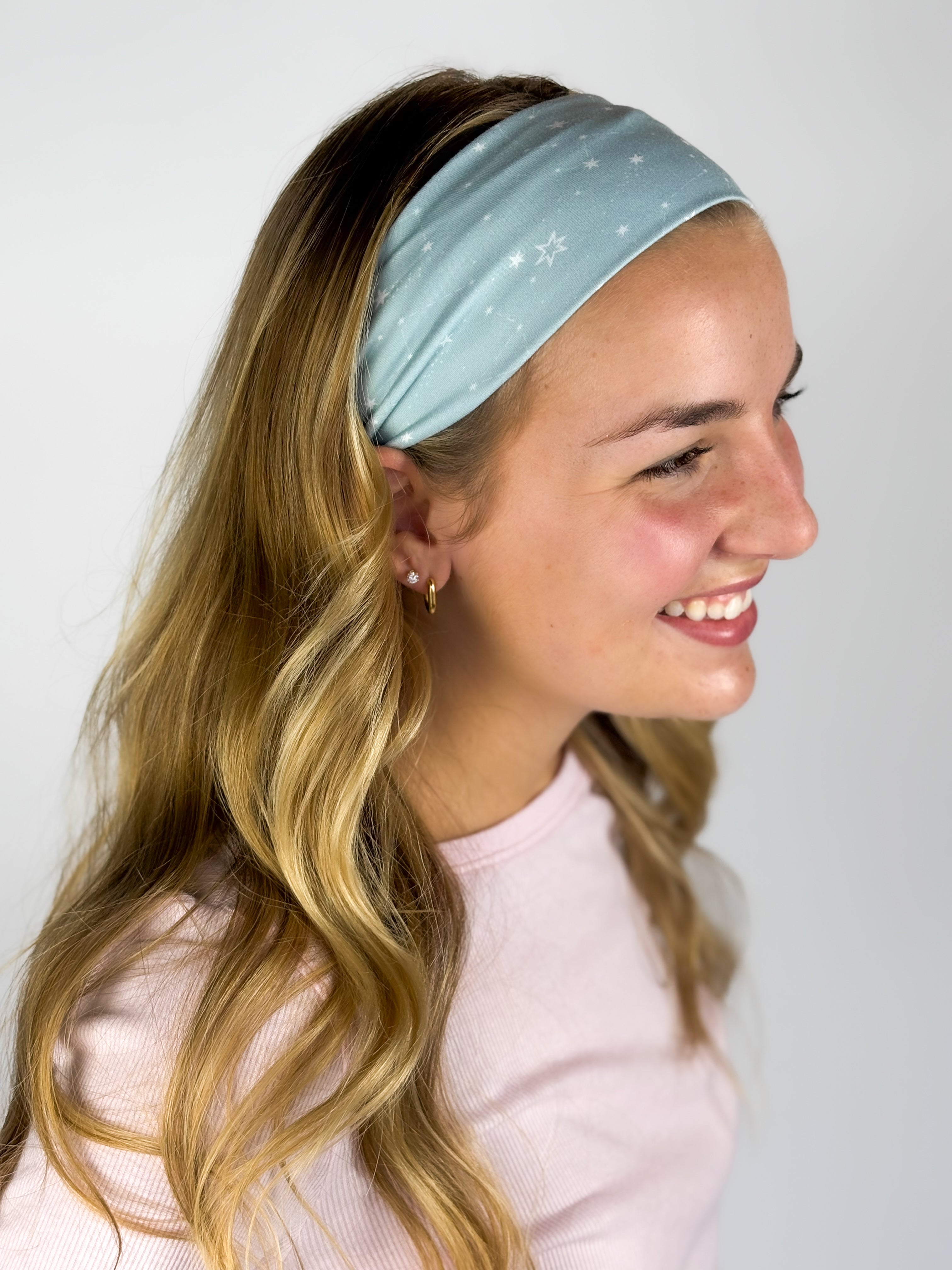 Woman wearing the Lost in Space headband, showcasing its versatile 3-in-1 twist style and buttery-soft, non-slip fabric, ideal for work or play.