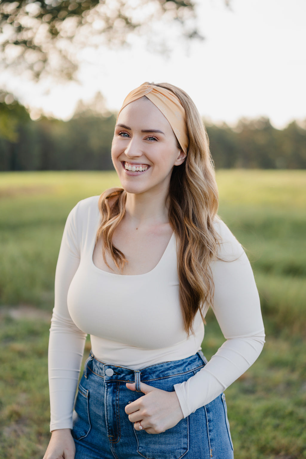Woman smiling outdoors, wearing the Bring the Weather headband from The Jen Hamilton Collection, showcasing its versatile, non-slip, buttery-soft design.