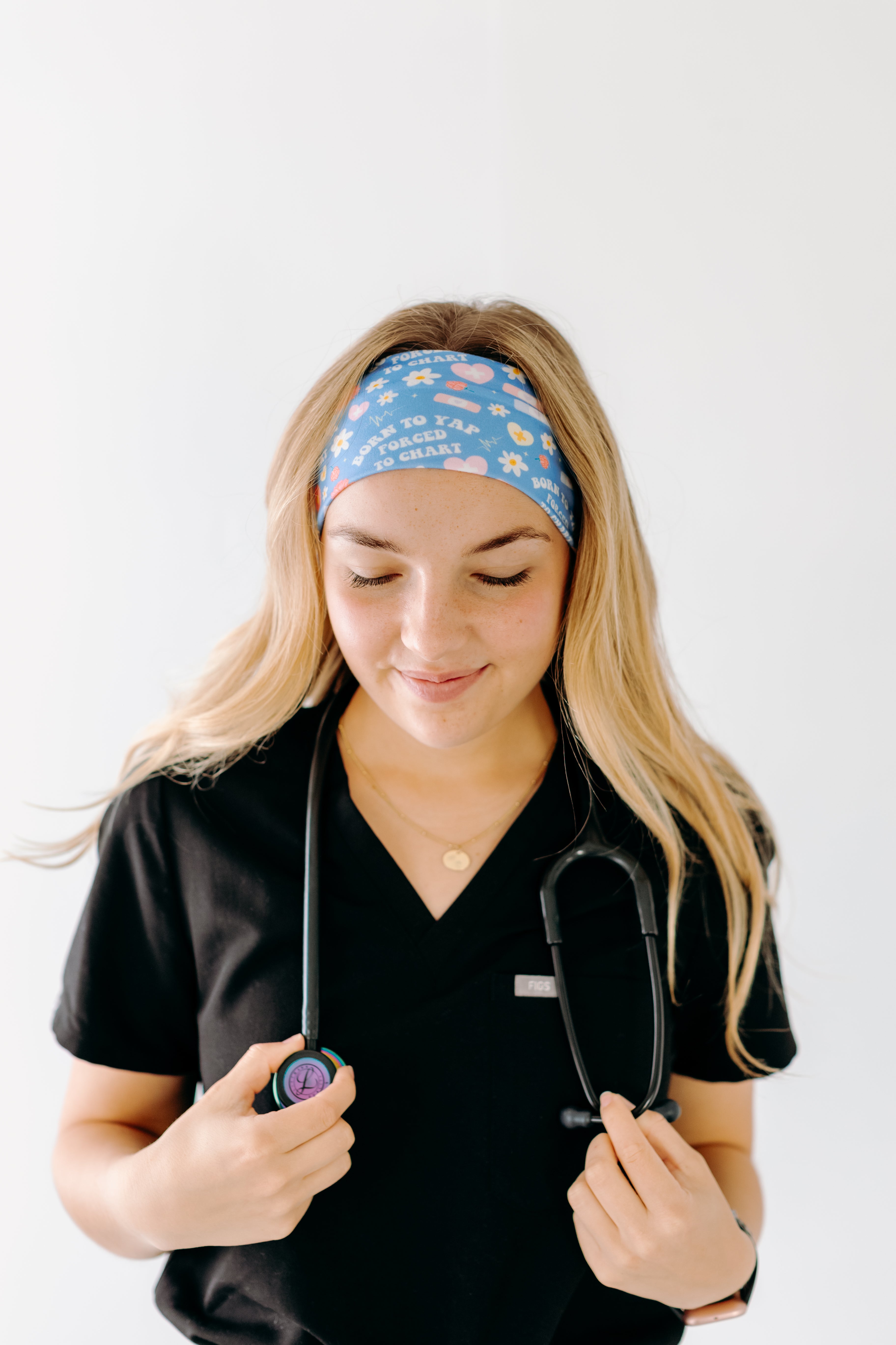 A nurse smiling with long hair while wearing the Born to Yap Forced to Chart headband for cute hairstyles and comfortable all-day wear.