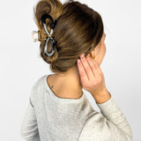 Woman confidently wearing the Treat Yourself Lilac Clip in her hair, featuring a 4-inch glossy metal claw design with hinge closure, styled in a twist.
