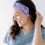 A nurse smiling with long hair while wearing the Ask Us About Our Warm Blankets headband for cute hairstyles and comfortable all-day wear.