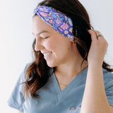 A nurse smiling with long hair while wearing the Ask Us About Our Warm Blankets headband for cute hairstyles and comfortable all-day wear.