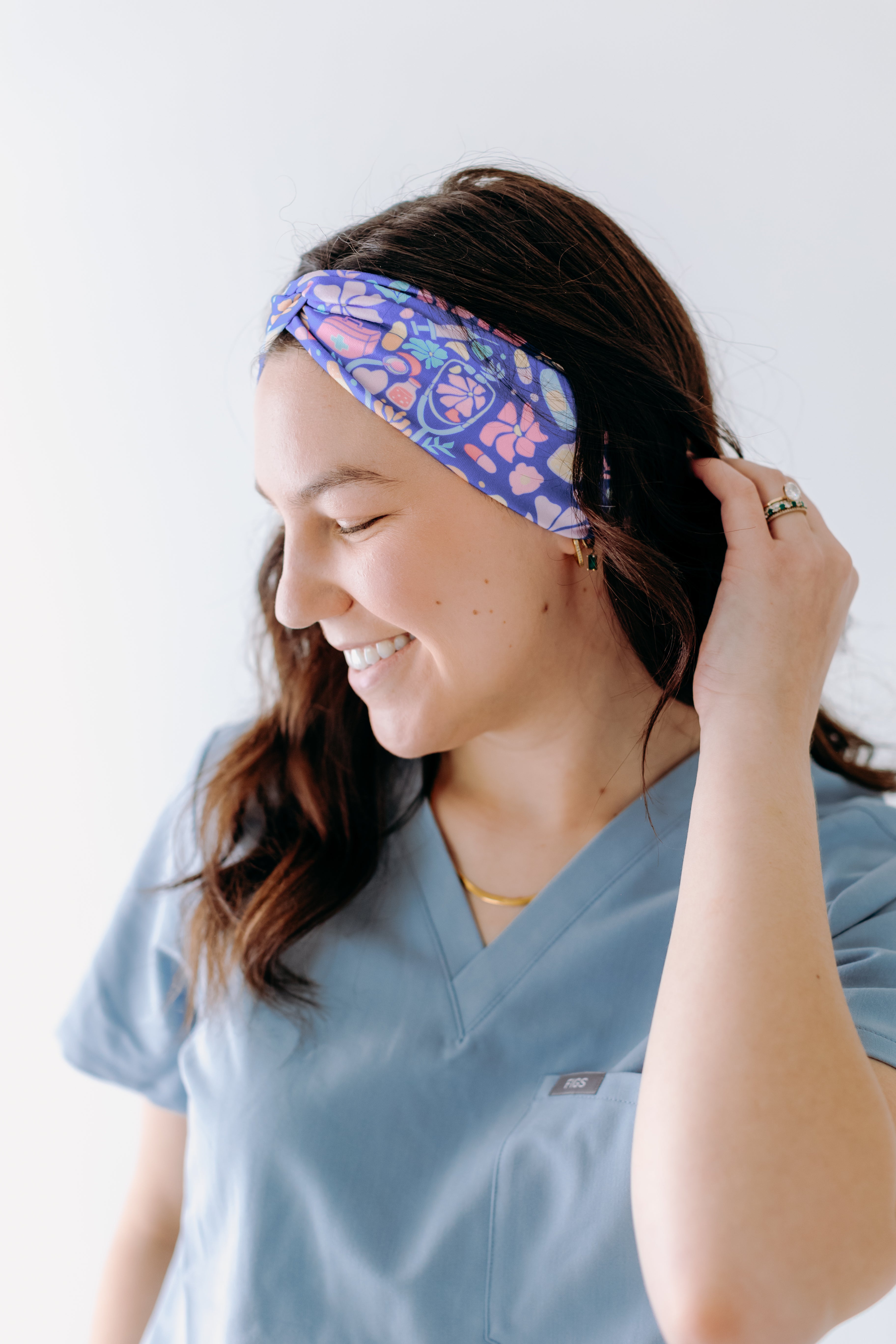 A nurse smiling with long hair while wearing the Ask Us About Our Warm Blankets headband for cute hairstyles and comfortable all-day wear.