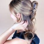 A woman wearing the Effortless Lilac Clip, a glossy hair accessory, in a dress with long hair.