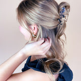 A woman wearing the Effortless Lilac Clip, a glossy hair accessory, in a dress with long hair.