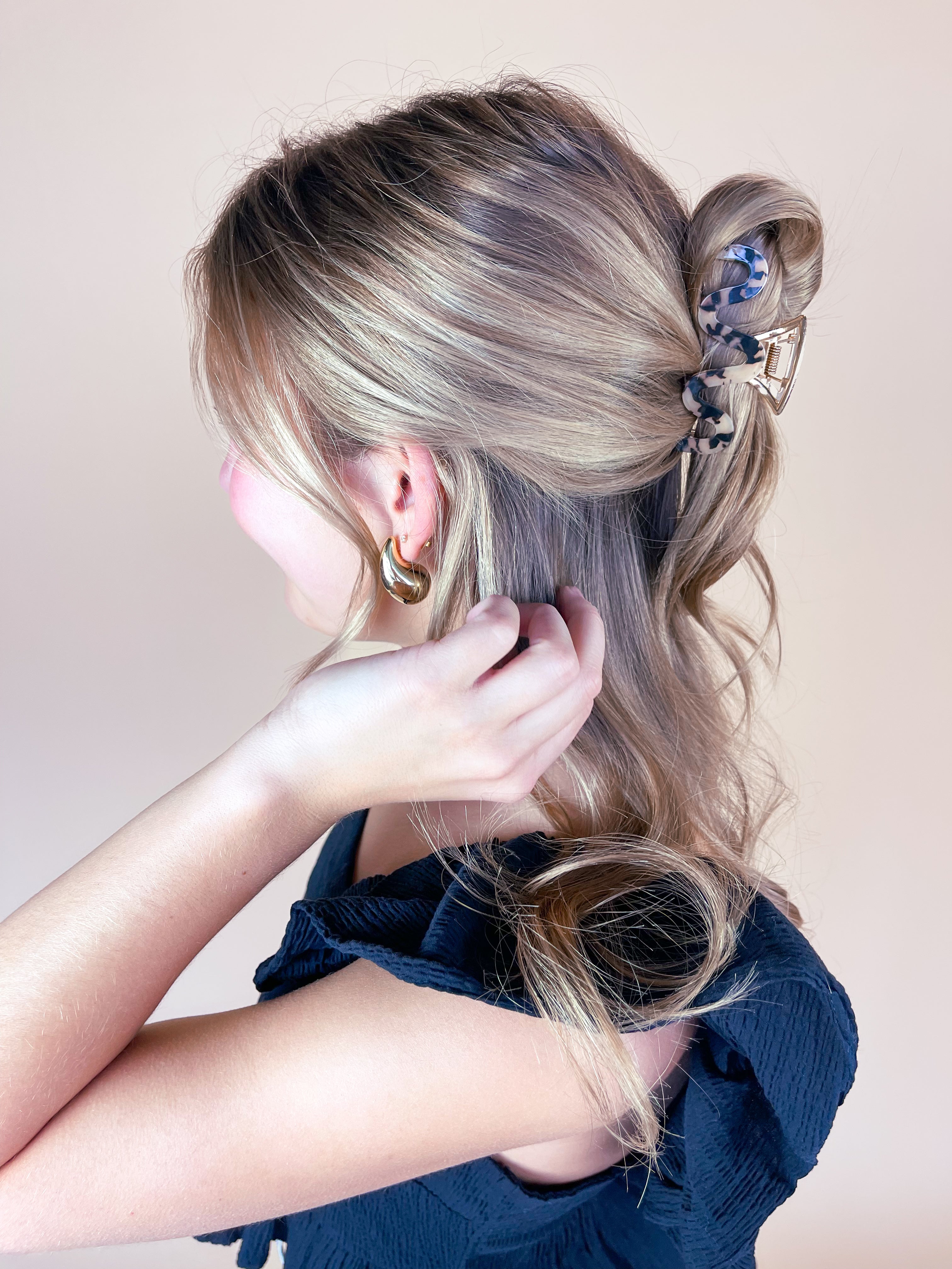 A woman wearing the Effortless Lilac Clip, a glossy hair accessory, in a dress with long hair.