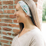 A woman smiling and confidently wearing the Springtime in Brooklyn headband from The Sarah Wallace Collection, showcasing its versatile twist style and non-slip design.
