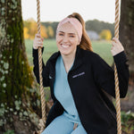 Woman in scrubs on a swing wearing a Nurse headband, showcasing its versatile, non-slip design, perfect for workouts or long shifts.