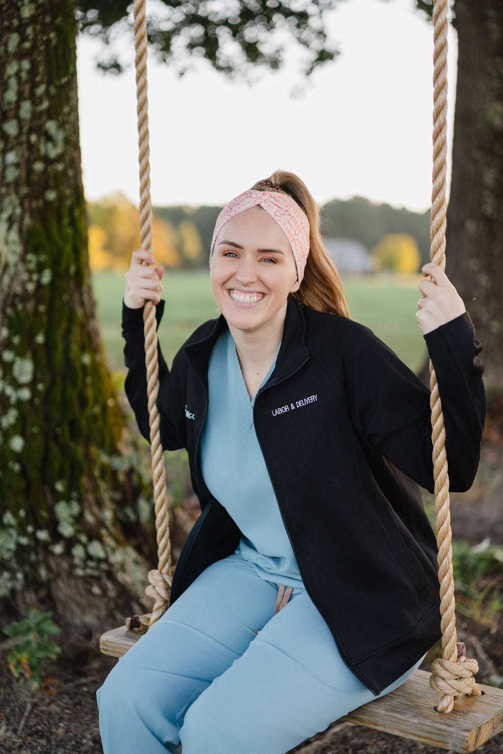 Woman in scrubs on a swing wearing a Nurse headband, showcasing its versatile, non-slip design, perfect for workouts or long shifts.