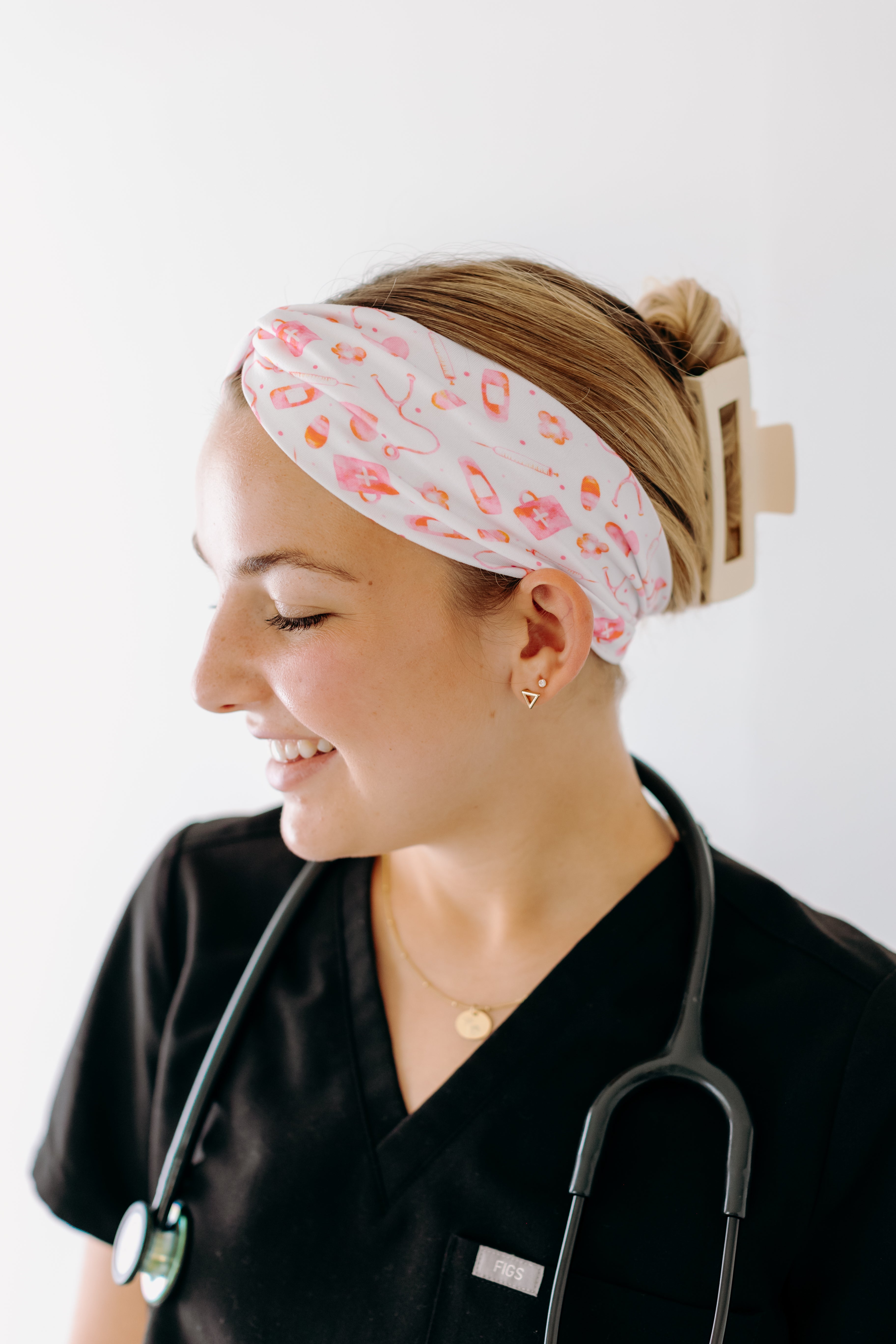 A nurse smiling with hair pinned up while wearing the I'm Just Here For The Free Gloves headband for cute hairstyles and comfortable all-day wear.