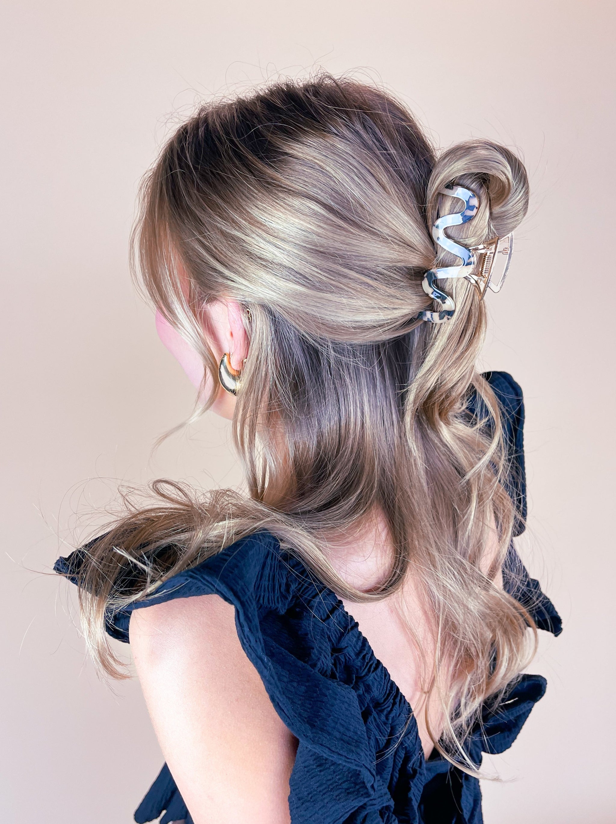 A woman wearing the Effortless Lilac Clip, a glossy hair accessory, in a dress with long hair.