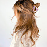 A woman wearing the Head in the Clouds Lilac Clip, a 2-inch long claw clip, adding style to her hair.