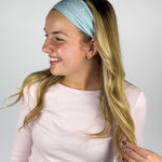 Woman wearing the Lost in Space headband, showcasing its versatile 3-in-1 twist style and buttery-soft, non-slip fabric, ideal for work or play.