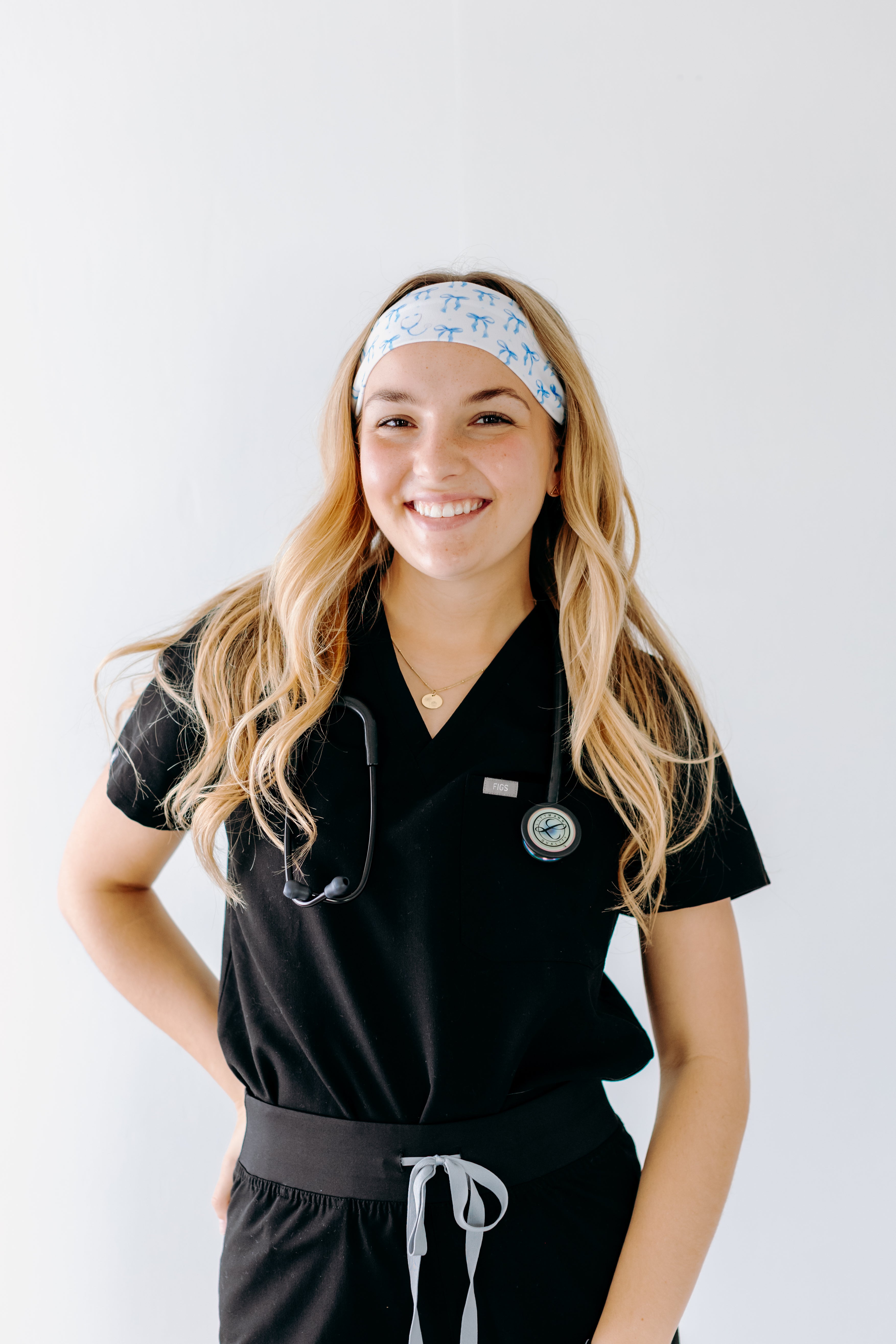 A nurse smiling with long hair while wearing the Nurses Do It Better headband for cute hairstyles and comfortable all-day wear.