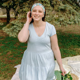 Woman smiling while wearing the Hope Floral on Ivory headband, the perfect non-slip accessory for work or workouts.