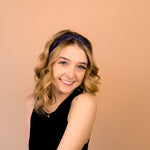 A woman wearing the Better in Black headband, a functional and versatile accessory for workouts, shifts, and play days.