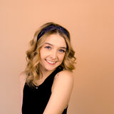 A woman wearing the Better in Black headband, a functional and versatile accessory for workouts, shifts, and play days.