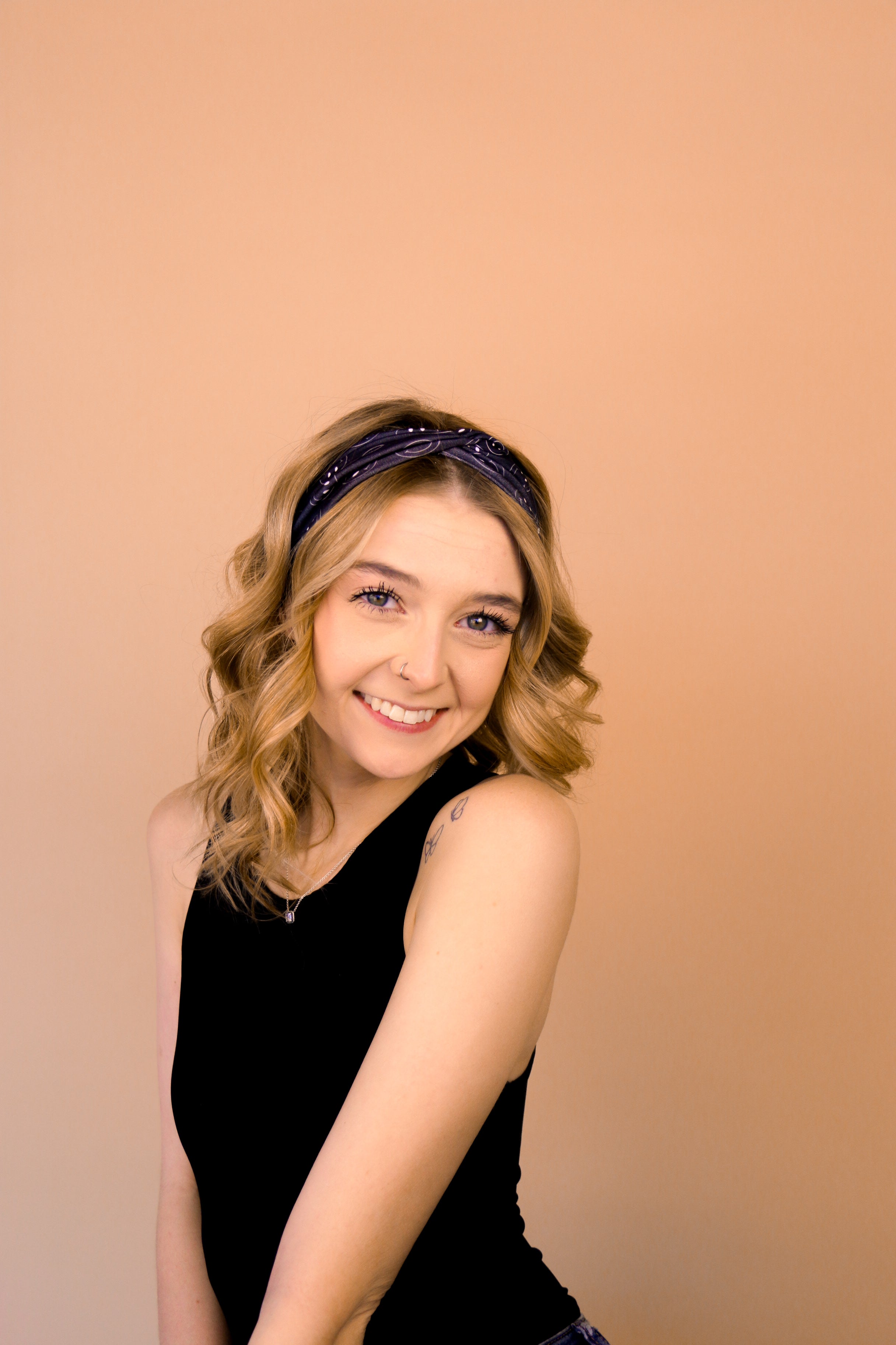 A woman wearing the Better in Black headband, a functional and versatile accessory for workouts, shifts, and play days.