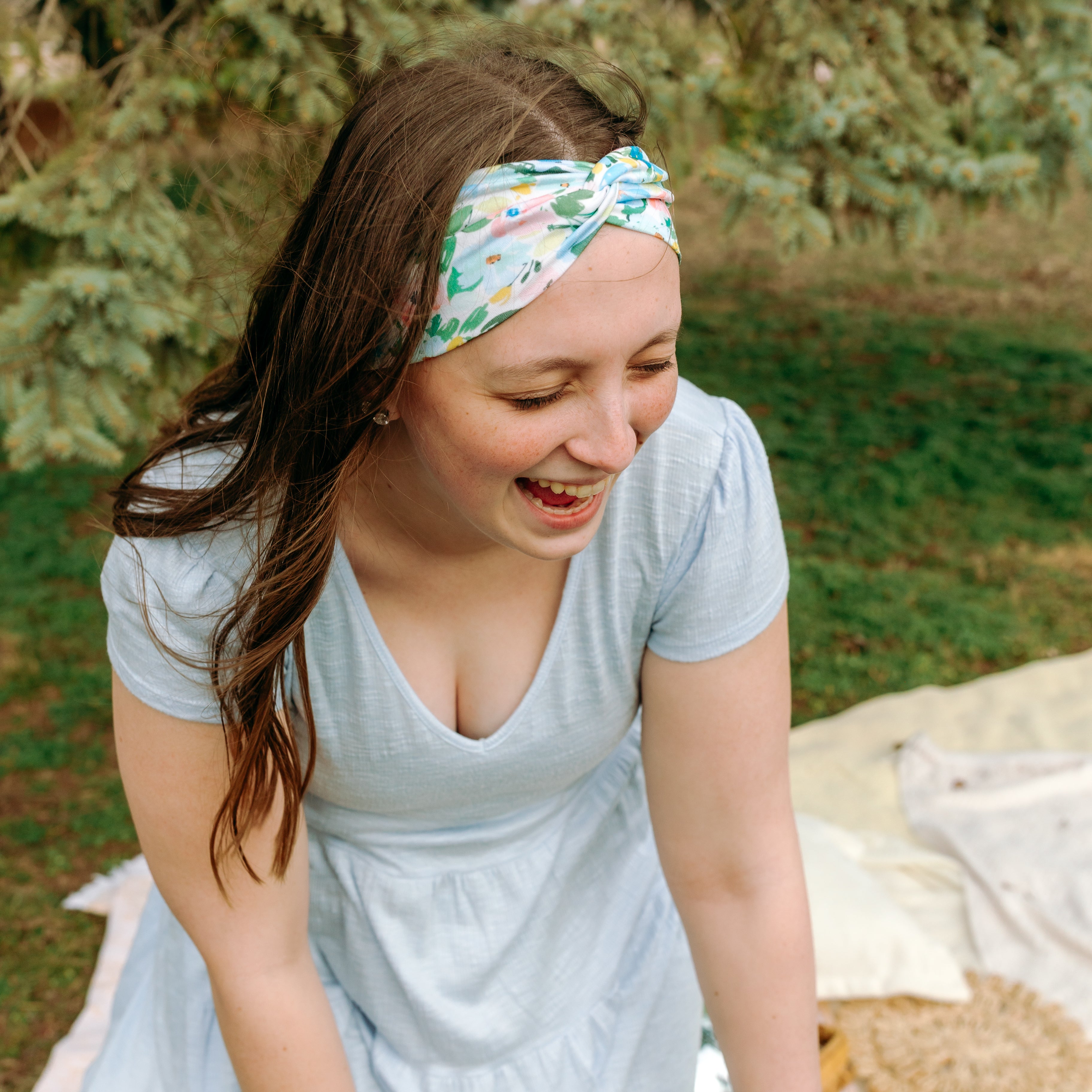 Woman smiling while wearing the Hope Floral on Ivory headband, the perfect non-slip accessory for work or workouts.