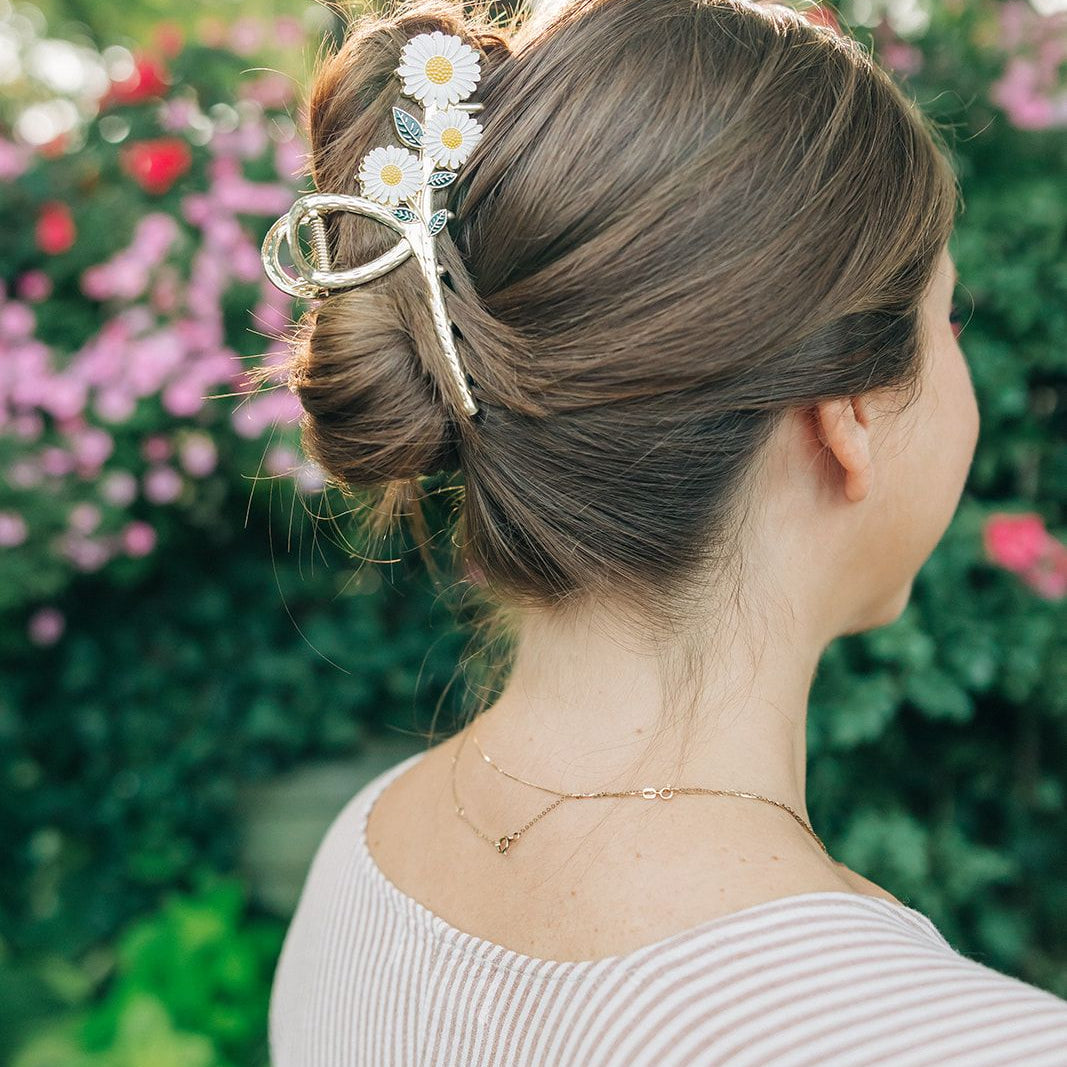 Woman wearing the Grow With Grace Clip from The Sarah Wallace collection, a 4.4-inch metal hair accessory with a flower design, securing her hair in a bun.