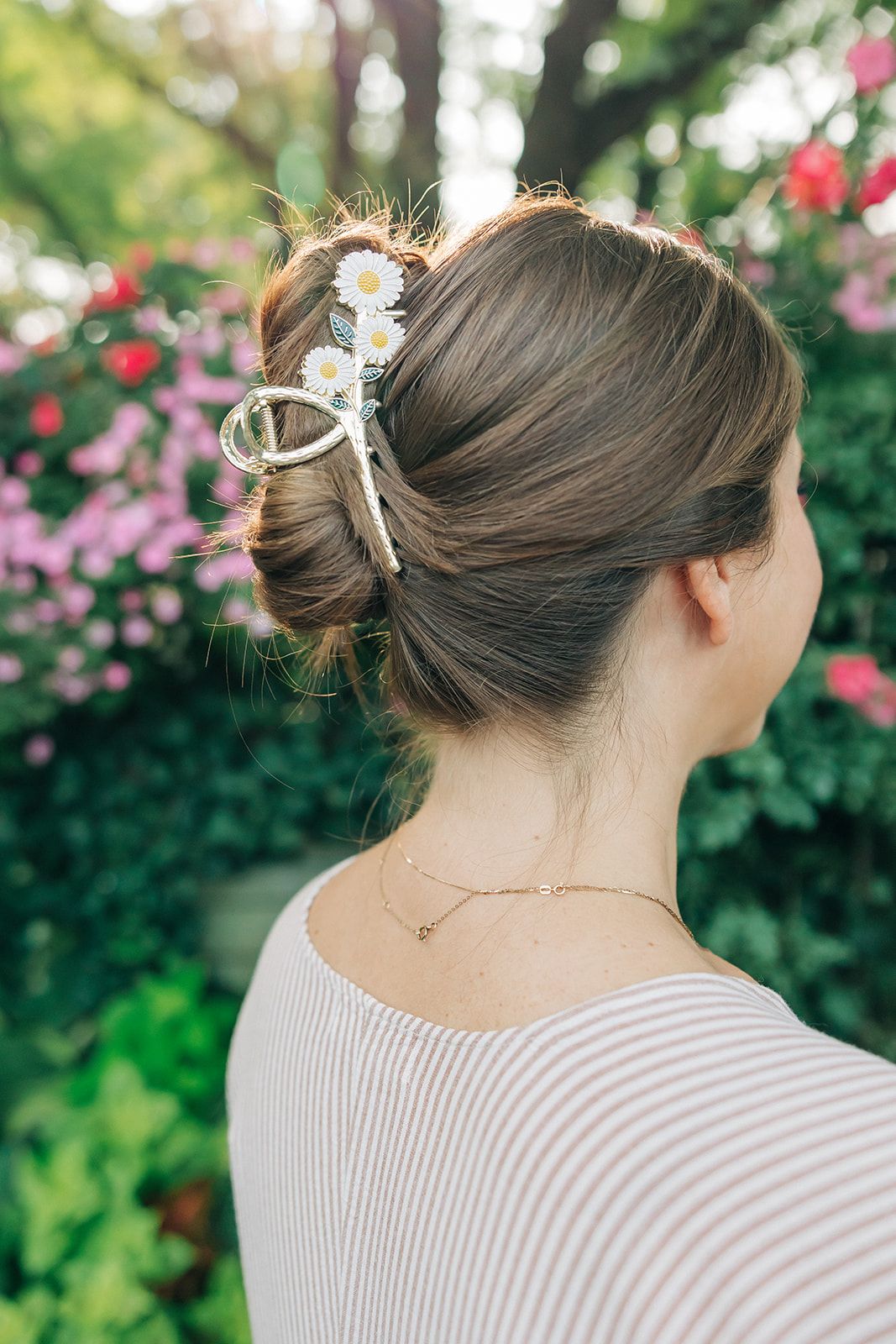 Woman wearing the Grow With Grace Clip from The Sarah Wallace collection, a 4.4-inch metal hair accessory with a flower design, securing her hair in a bun.
